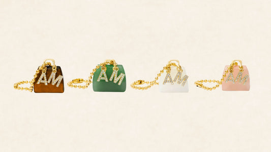 Crystal handbag charms with gold chains displayed on a neutral luxury background — includes Rose Quartz, Aventurine, and Tiger’s Eye for energy alignment.