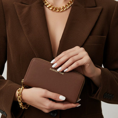 Woman holding a brown manifestation wallet representing stability, confidence, and grounded money energy
